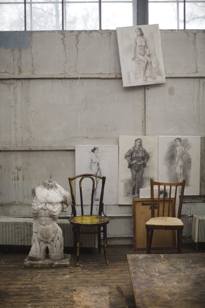 pexels-photo-3778080 Interior view of an art studio featuring a Greek sculpture, chairs, and drawings.
